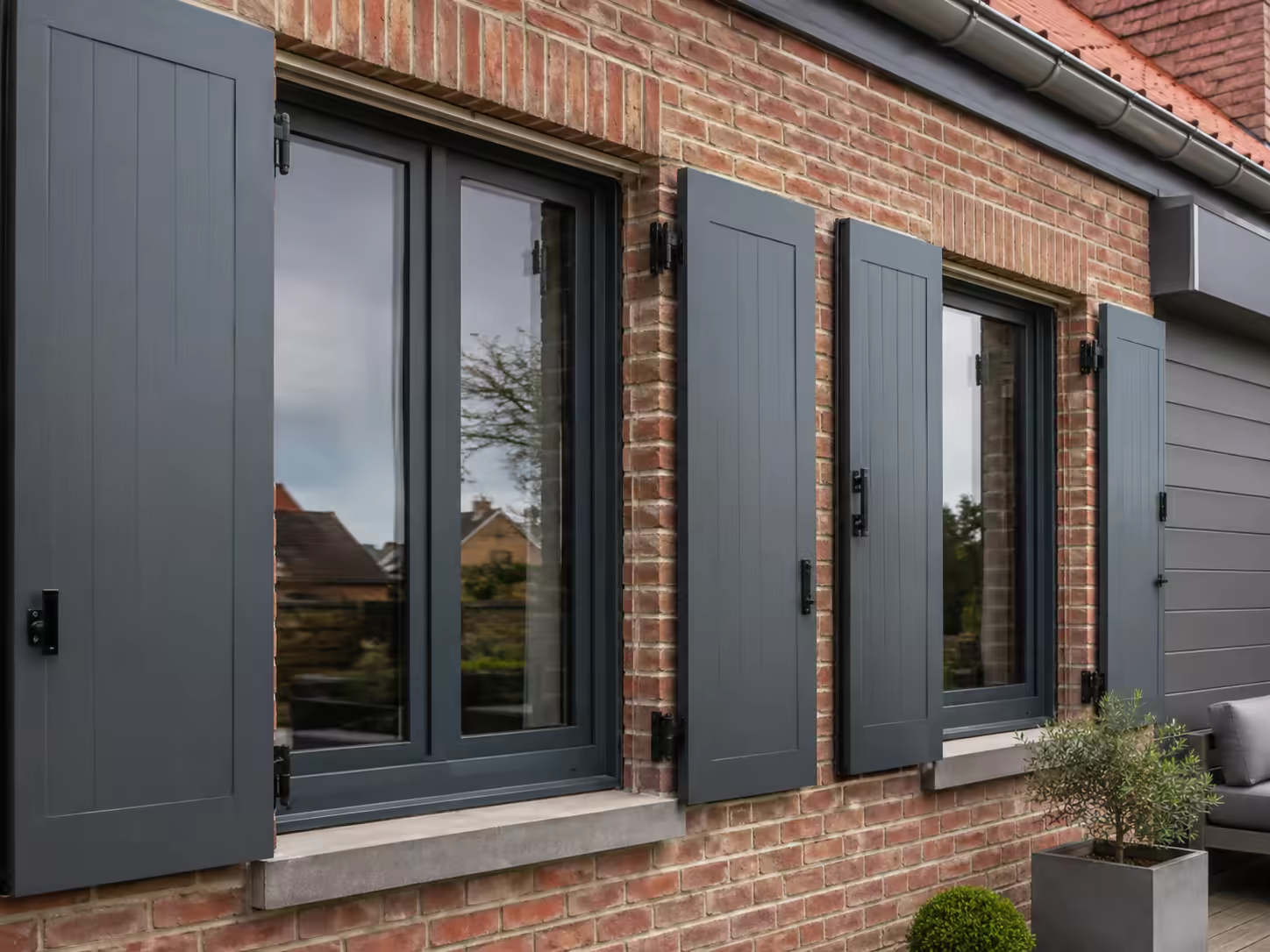 Façade de brique aux menuiseries et volets gris anthracite, après rénovation
