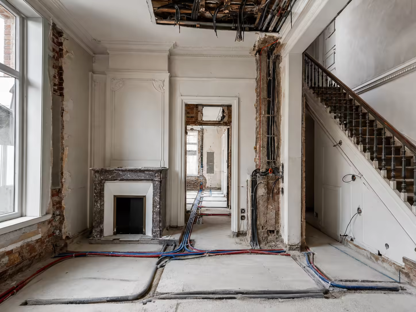 Appartement ancien mis à nu, escalier à balustrade conservé et réseaux passés au sol avant remise en état