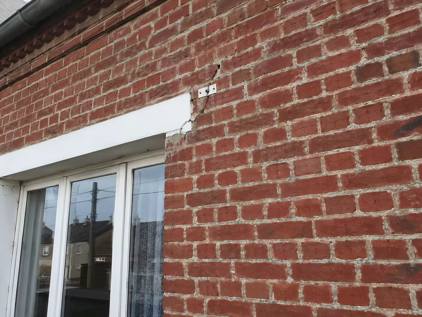 Maison en brique à Hazebrouck avec fissure oblique partant de l’angle d’une baie