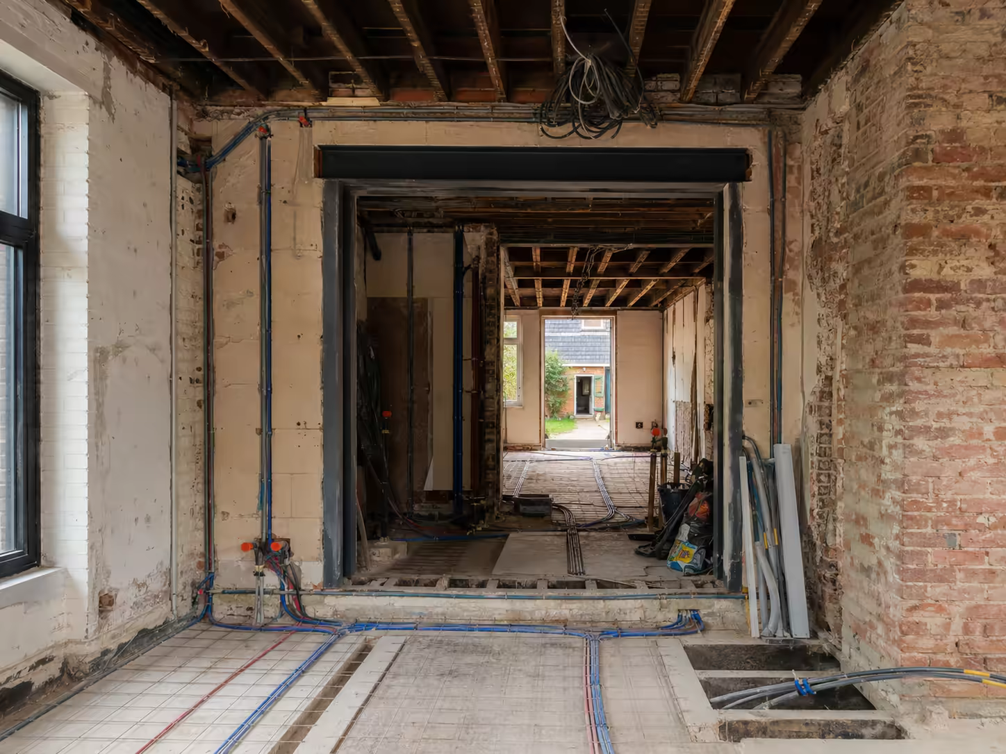 Ouverture pratiquée dans un mur porteur en brique avec linteau métallique posé et solives apparentes