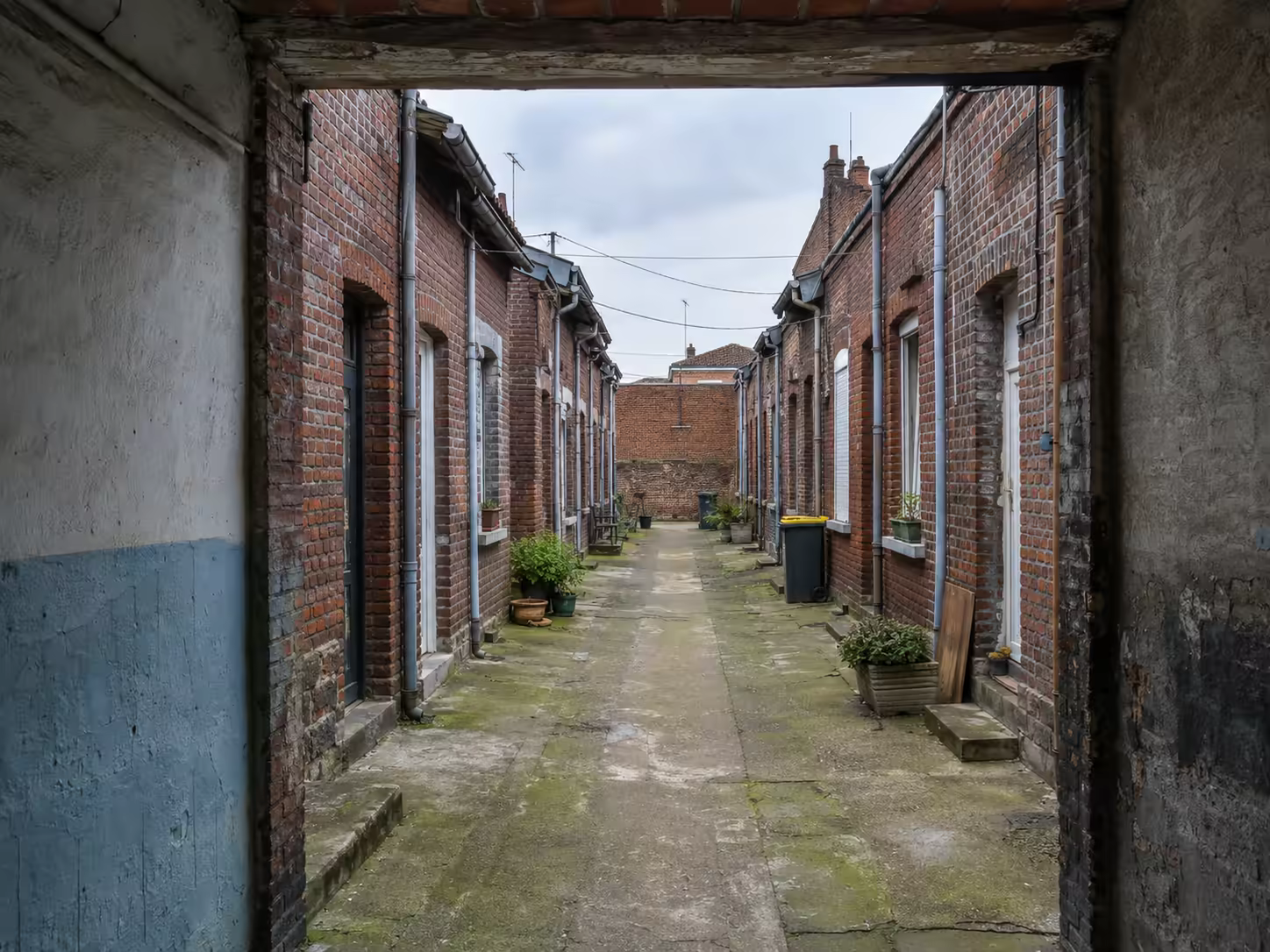 Courée roubaisienne avec rangées de petites maisons en brique autour d’un passage commun