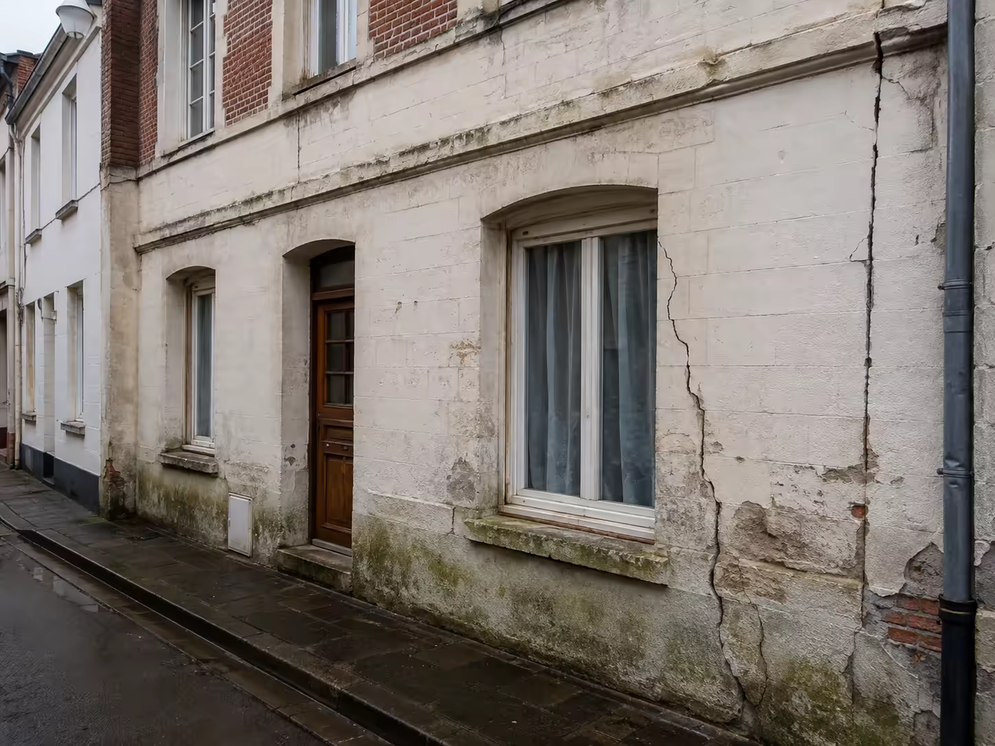Maison audomaroise avec fissure de tassement surveillée près du pied de façade