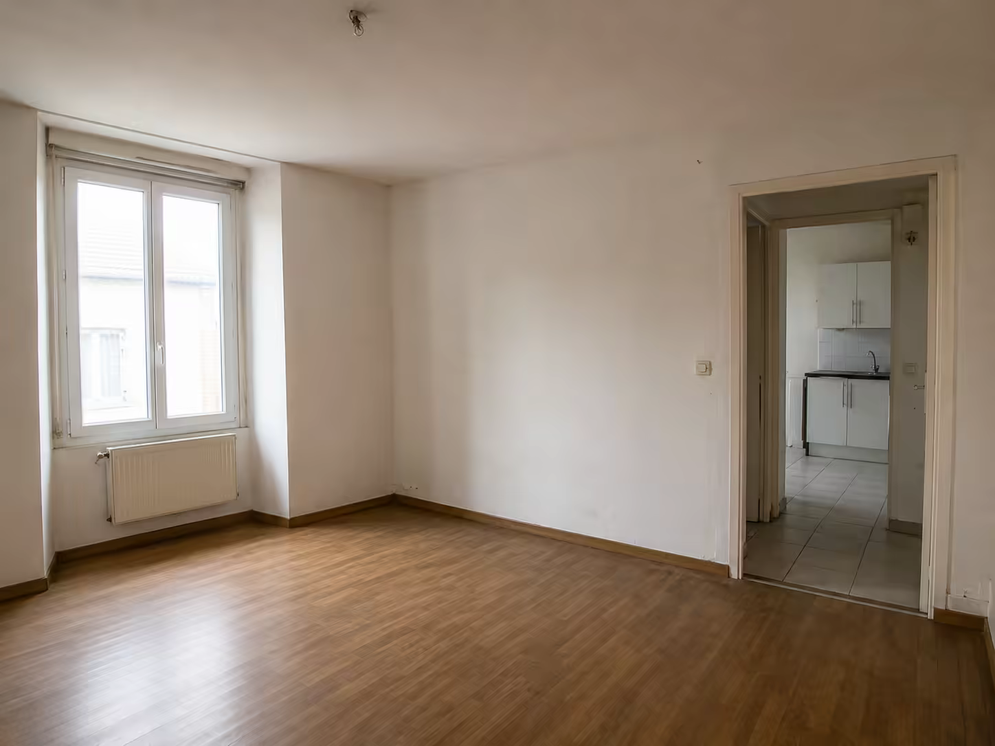 Pièce vide au parquet ancien, murs repeints en blanc, prête pour la suite du chantier