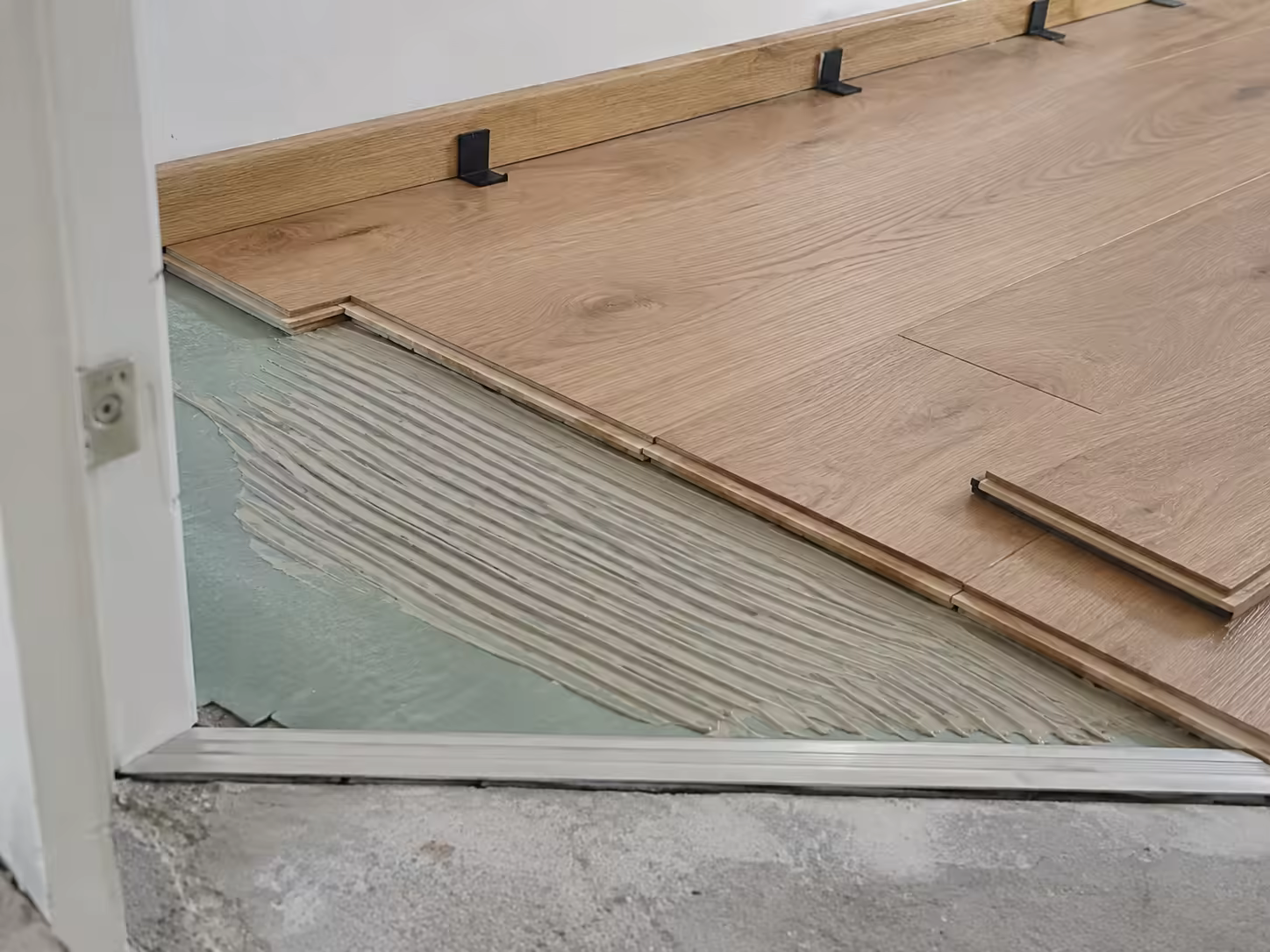 Pose d’un parquet flottant sur sous-couche, lames alignées et cales de dilatation en place