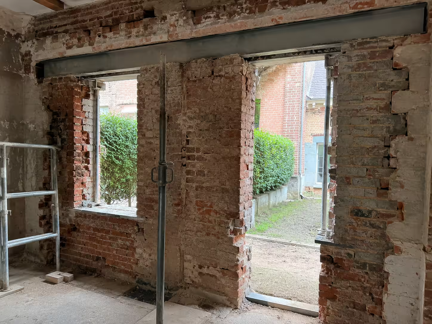 mur ancien en brique ouvert avec linteau et jambages visibles