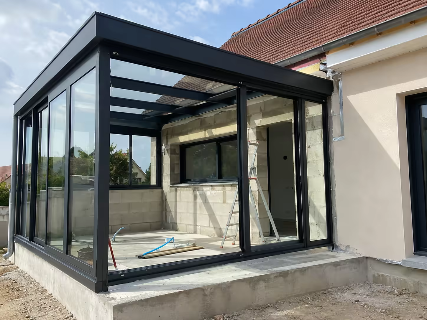 véranda en construction avec structure vitrage toiture dalle et raccord maison