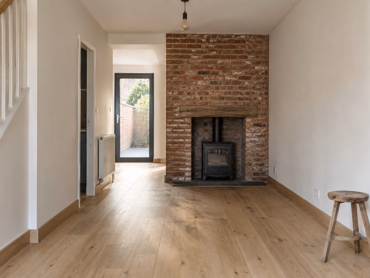 Un séjour de maison en brique entièrement rénové, mur de brique conservé, parquet clair, lumière traversante