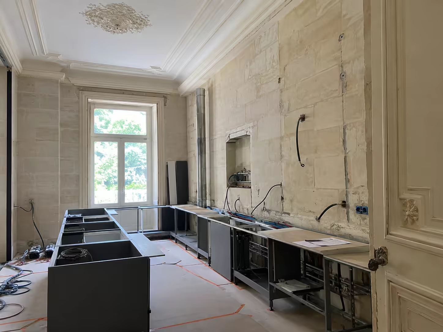 Îlot et meubles bas de cuisine en cours d’installation dans une pièce ancienne à mur de pierre appareillée
