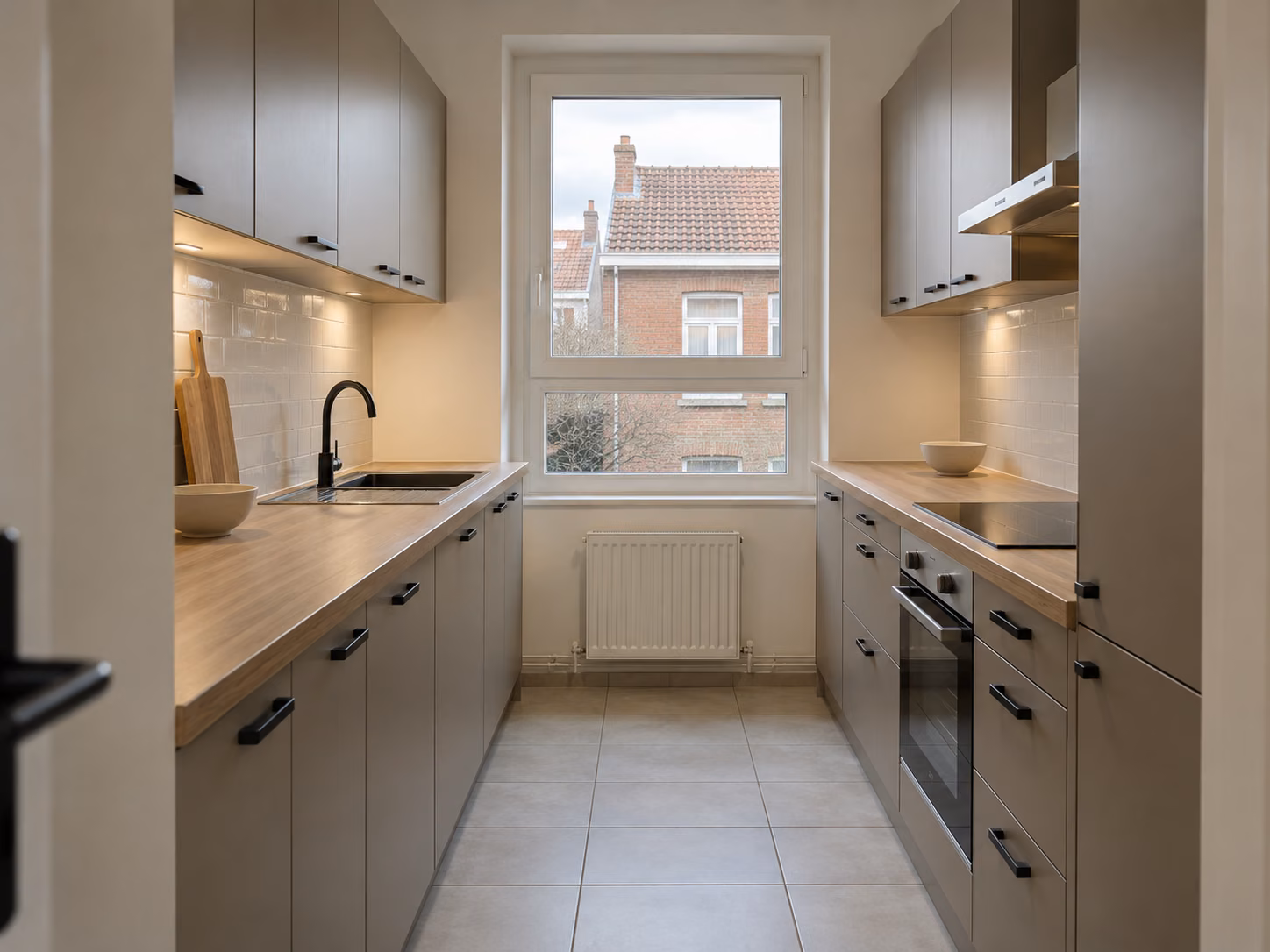 Une cuisine équipée terminée dans une maison de ville, façades mates, plan de travail bois, crédence carrelée