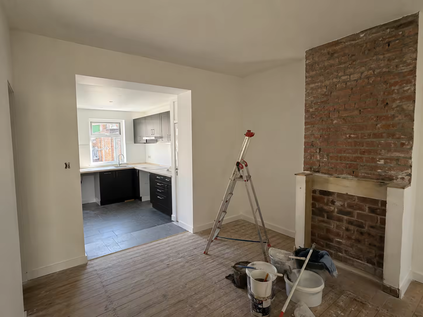 Cheminée en brique dégagée, cuisine neuve visible en enfilade