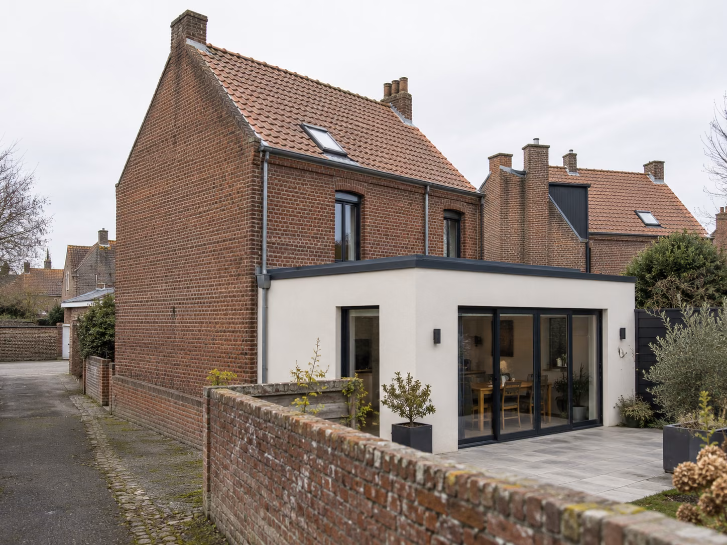 Une maison de ville en brique avec une extension arrière moderne visible depuis la rue latérale