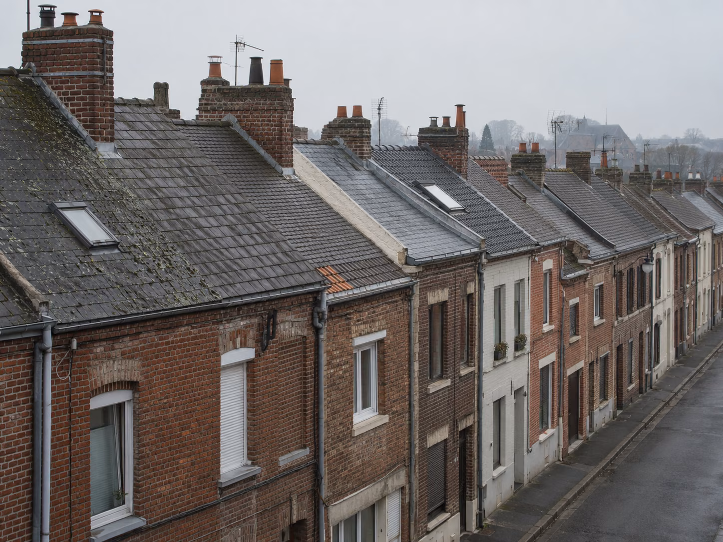 Une rangée de maisons en bande avec toitures en ardoise et souches de cheminée alignées, vue en légère plongée
