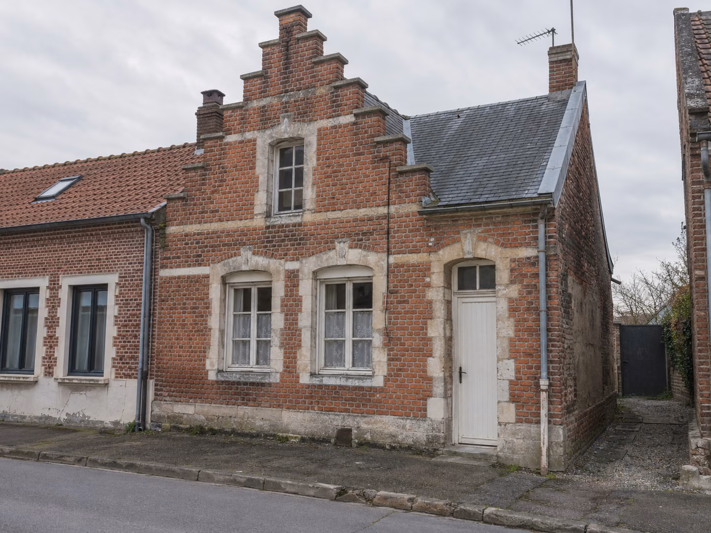 Une maison flamande à pignon sur rue, brique rouge et pierre blanche, fenêtres à petits bois