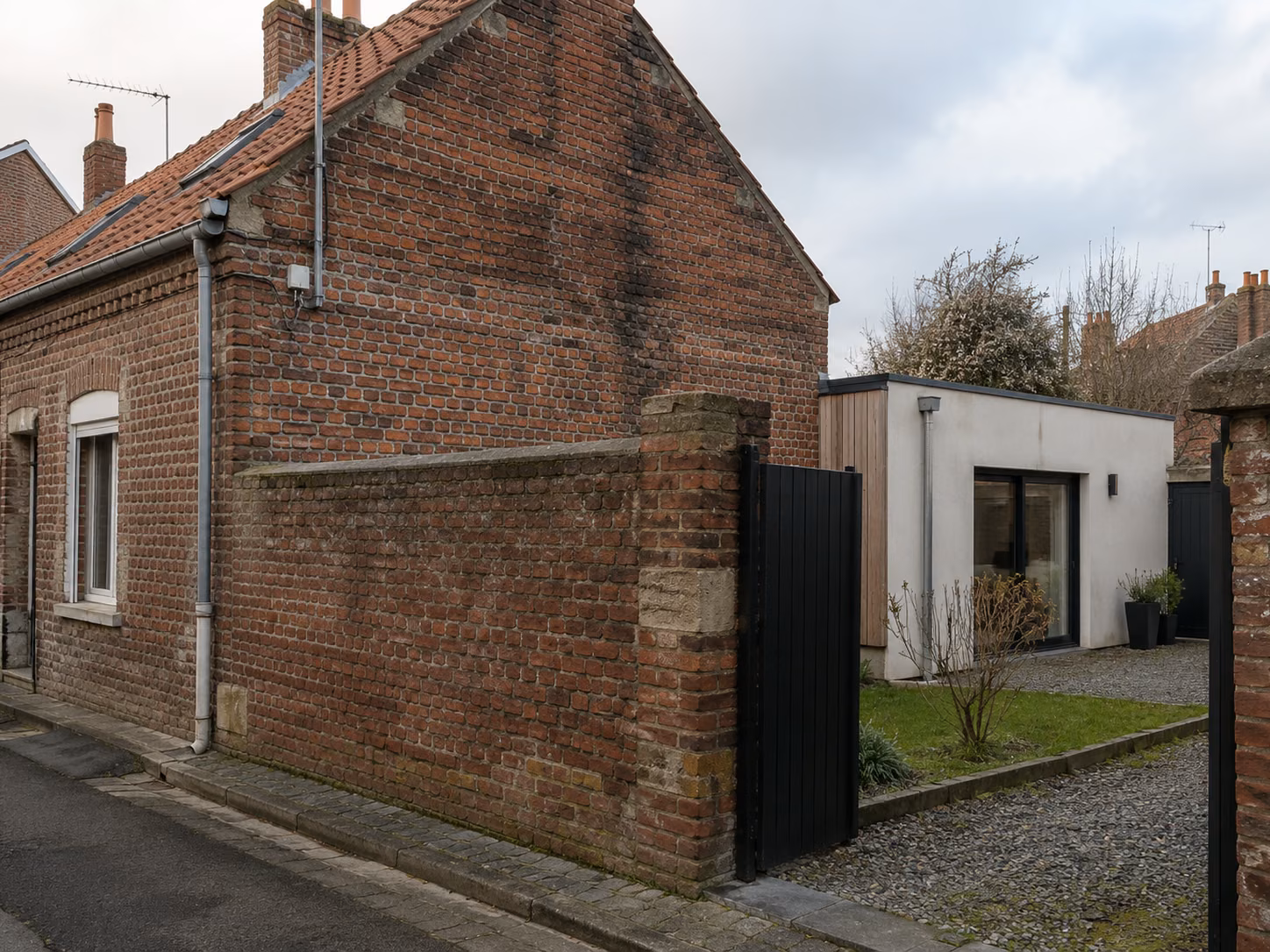 Une maison de ville en brique avec une extension arrière moderne visible depuis la rue latérale