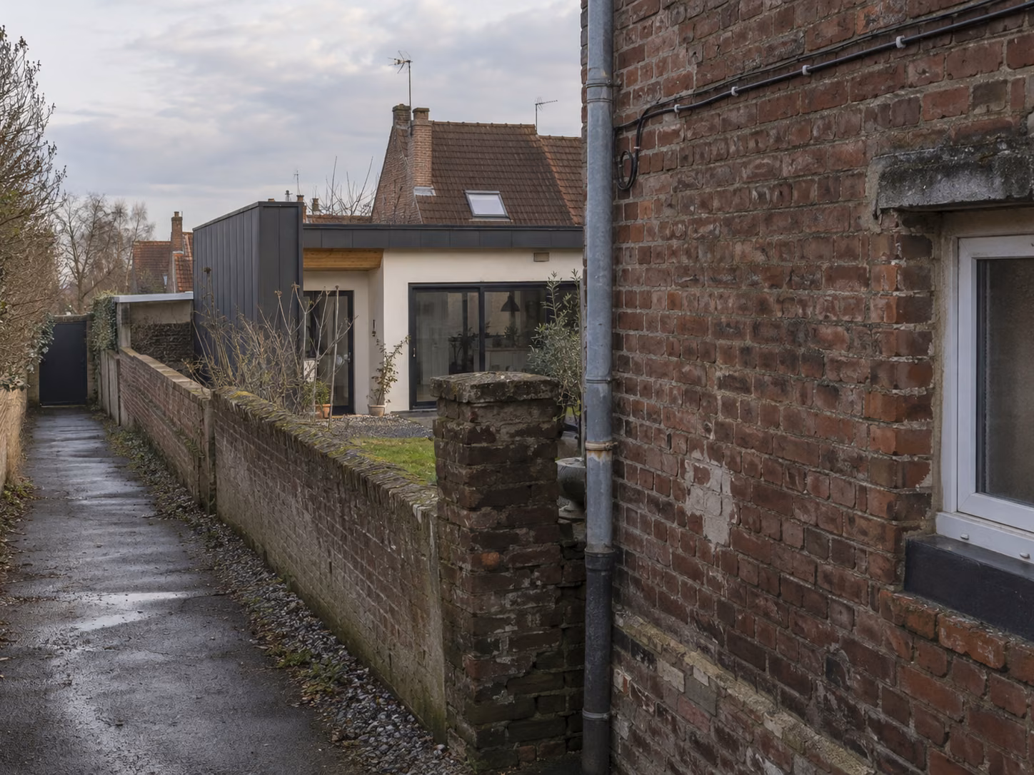 Une maison de ville en brique avec une extension arrière moderne visible depuis la rue latérale