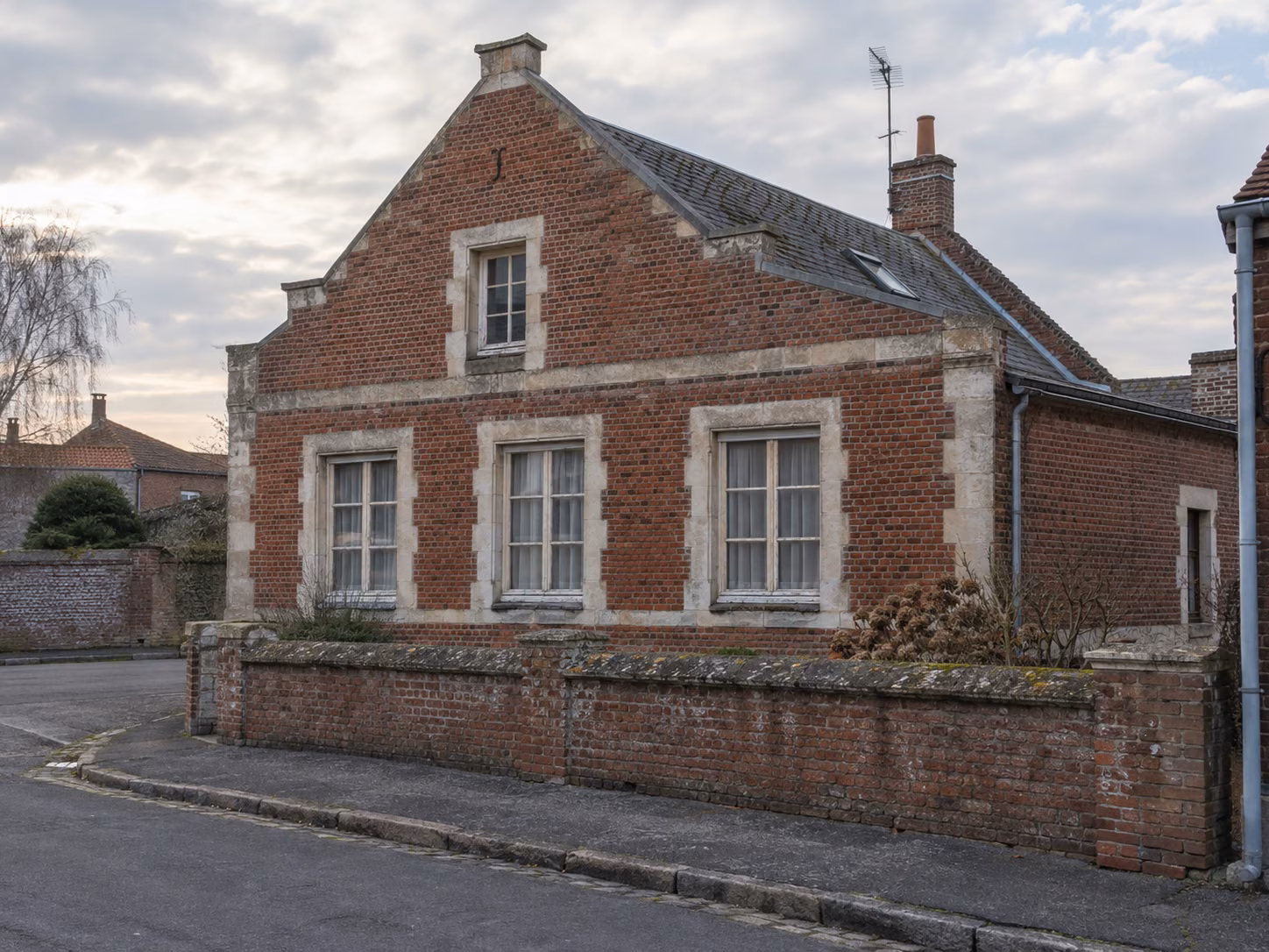 Une maison flamande à pignon sur rue, brique rouge et pierre blanche, fenêtres à petits bois