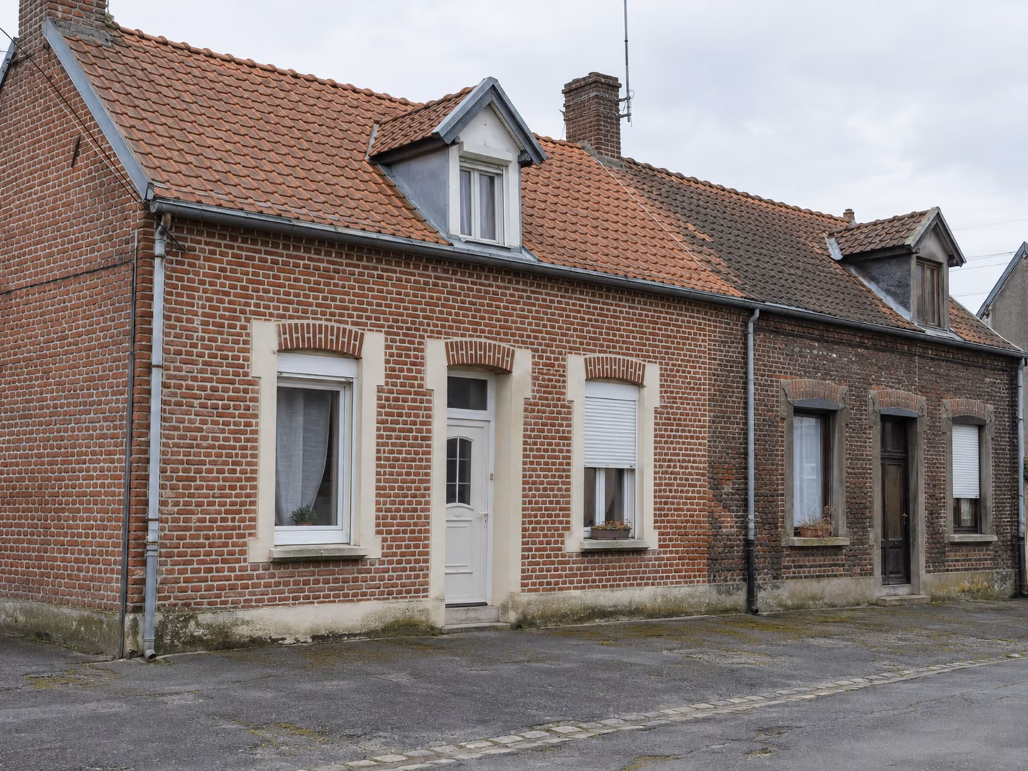 Une façade en brique avec un ravalement récent d’un côté et une façade voisine non traitée, contraste visible